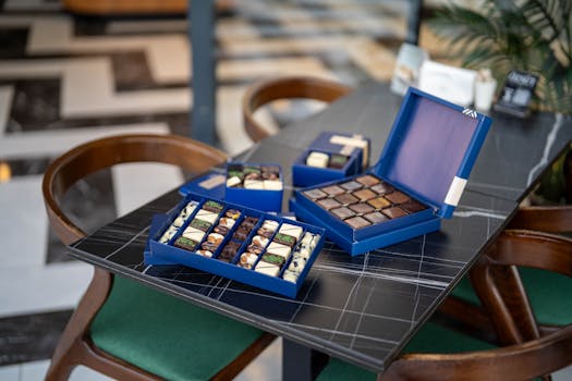 Boîte de chocolats raffinés sur une table, avec des assortiments de pralinés et de chocolats fins.