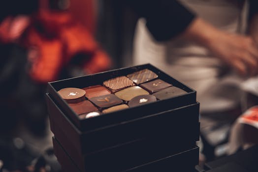 Boîte de chocolats assortis avec des pralinés élégamment présentés sur une table.